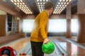 Bowler with green bowling ball ready to take his shot, poised to roll ball down shiny lanes of modern bowling alley Royalty Free Stock Photo