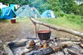 Bowler with soup on campfire and tourist tents