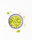 A bowlful of green gooseberries on a white background