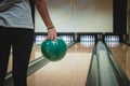 Bowling girl prepares for her throw on a specially modified bowling alley. Spending free time. A woman holds a green ball and Royalty Free Stock Photo