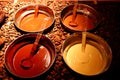 Bowls with colorful melted chocolate on brown roasted cocoa beans background. Milky, black, white and brown chocolate.