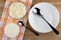 Bowls with cottage cheese, sour cream, spoon on napkin, spoon in plate on table. Top view Royalty Free Stock Photo