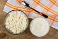 Bowls with cottage cheese, sour cream, spoon on napkin on table. Top view Royalty Free Stock Photo