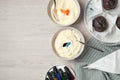 Bowls of different cream with food coloring, bottles of bright liquid and cupcakes on white wooden table, flat lay. Space for text Royalty Free Stock Photo