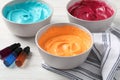 Bowls of different cream with food coloring and bottles of bright liquid on white wooden table Royalty Free Stock Photo