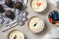 Bowls of different cream with food coloring, cupcakes, bottles of bright liquid and spoons on white wooden table, flat lay Royalty Free Stock Photo