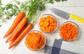 Bowls of differently cut carrots on white background