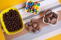 Bowls filled with different kinds of brown and colorful chocolates of different colors and shapes