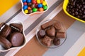 Bowls filled with different kinds of brown and colorful chocolates of different colors and shapes