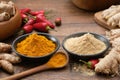 Bowls of ginger and curcuma ground to powder. Red chilli pepper pods, whole ginger and turmeric roots on kitchen table. Royalty Free Stock Photo