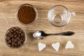 Bowls with ground coffee, coffee beans, empty cup, spoon, pieces of sugar on wooden table. Top view Royalty Free Stock Photo