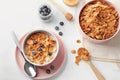 Bowls with healthy cornflakes, milk and blueberry on white table