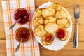 Bowls with jams on napkin, fried pancakes in dish, fork on table. Top view