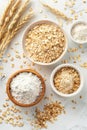 Bowls of oat flakes and flour with wheat stalks on a light surface. Royalty Free Stock Photo