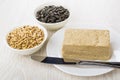 Bowls with peeled and unpeeled sunflower seeds, plate with halva Royalty Free Stock Photo