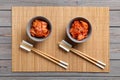 Bowls of spicy cabbage kimchi and chopsticks on wooden table, flat lay Royalty Free Stock Photo