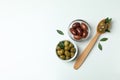 Bowls and spoon of olives, and leaves on white background Royalty Free Stock Photo