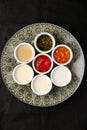 Bowls of various sauces on plate and black background top view Royalty Free Stock Photo