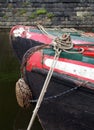 Bows of two traditional old narrow boats moored on a canal surrounded by a stone wall