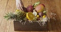 Woman`s hand put wooden box with assortment of exotic fresh organic fruits on a wooden table. Motion, 4K UHD video, 3840