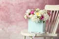 Box with beautiful flowers on wooden chair against color background Royalty Free Stock Photo