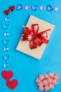 A box with a bow in a frame made of pebbles of hearts on a blue background. Royalty Free Stock Photo