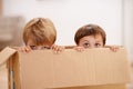 Box, children and eyes of siblings playing in a house with fun, bonding and hide and seek games. Cardboard, learning and Royalty Free Stock Photo