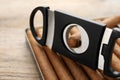 Box of cigars and guillotine cutter on wooden table, closeup