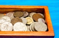 box with coins of countries of the world on a blue wooden background. money. a Palestinian, a Soviet, an Israeli, a Ukrainian coin