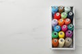 Box with colorful sewing threads on white marble table, top view. Space for text Royalty Free Stock Photo