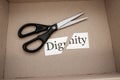 The box contains a strip of paper with the word dignity and scissors that cut this word Royalty Free Stock Photo