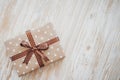 Box in craft paper, eco paper on the wooden table. Top view. Brown paper wrapped gift box with satin ribbon bow on a old Royalty Free Stock Photo