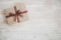 Box in craft paper, eco paper on the wooden table. Top view. Brown paper wrapped gift box with satin ribbon bow on a old Royalty Free Stock Photo