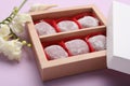 Box of delicious mochi and flowers on light background, closeup. Traditional Japanese dessert
