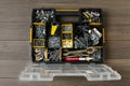 Box with different furniture fittings and tools on wooden table, top view