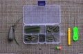 A box with elements of carp accessories lies next to the ready-made assembly, a needle and a drill for boilies