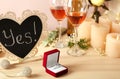 Box with engagement ring with glasses of wine and candles wooden table Royalty Free Stock Photo