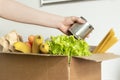 Box with food for delivery on a white background. A female hand in a medical glove puts can in a box with products. Concept of Royalty Free Stock Photo