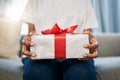 Box, gift and woman on a sofa in the living room with a giving gesture for celebration or event. Bow, wrapping paper and Royalty Free Stock Photo