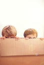 Box, kids and eyes of siblings playing in a house with fun, bonding and hide and seek games. Cardboard, learning and Royalty Free Stock Photo