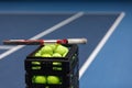 Box with tennis balls and tennis racket on tennis court Royalty Free Stock Photo