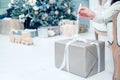 Box with Luxury Metallics gift on background of Christmas tree. Hands open New Year`s gift close-up, copy space Royalty Free Stock Photo