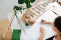 Box maker working behind a table, drawing scematics, tools scattered across