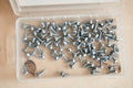 Box with metal self-tapping screws on wooden background. Short fix for aluminum and metal. Silver color. Hardware product store. Royalty Free Stock Photo