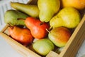 A box of multi-colored juicy pears on a light background Royalty Free Stock Photo