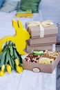 Box with nuts and dried fruits. Easter table. Yellow easter bunny, bouquet of yellow tulips.