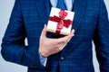 Box pack tied with elegant red ribbon being held in male hand formal style for holiday celebration, gift