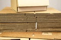 Box ready for product packaging and a stack of folded corrugated cardboard sheets on a table Royalty Free Stock Photo