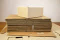 Box ready for product packaging and a stack of folded corrugated cardboard sheets on a table Royalty Free Stock Photo