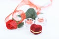 Box with ring, rose and two candles on white background